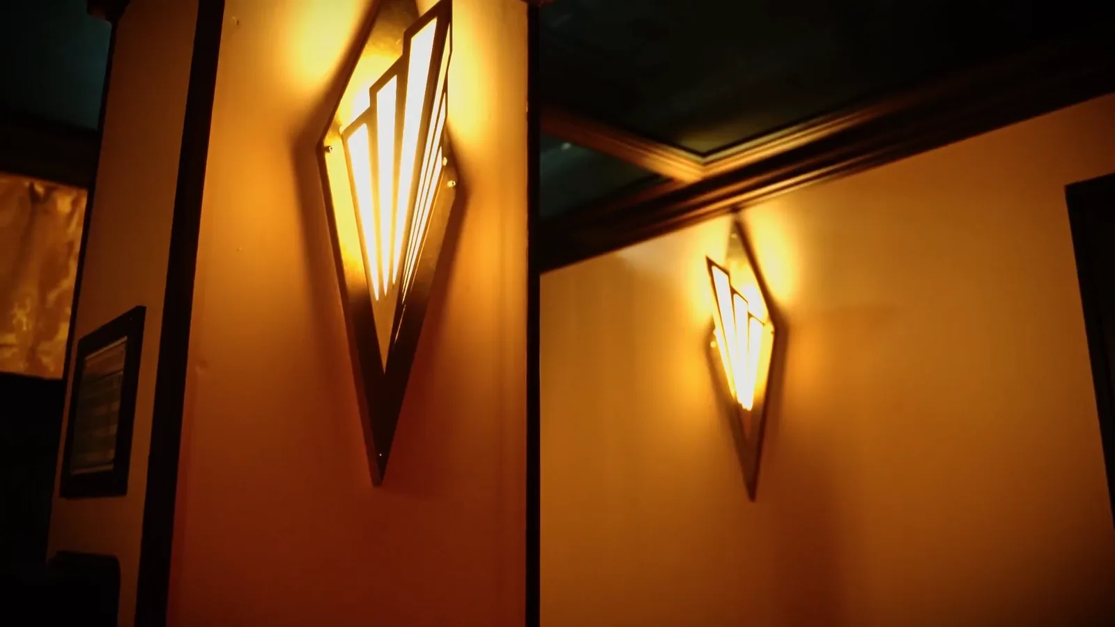 Fan-shaped Art Deco wall sconces glowing in a Hotel: Murder Mystery corridor